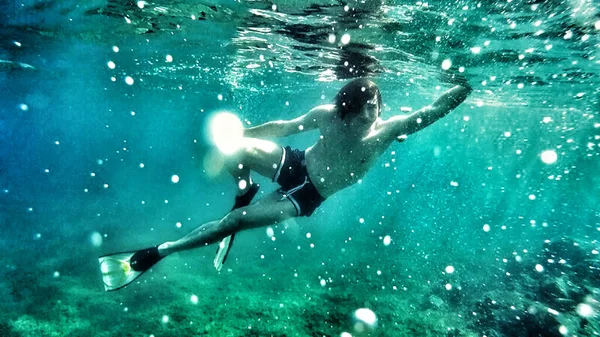 Underwater diving. Relaxation, sport, sunlight, travel, healthy lifestyle.  Guy is diving under water. Summer vacation concept.
