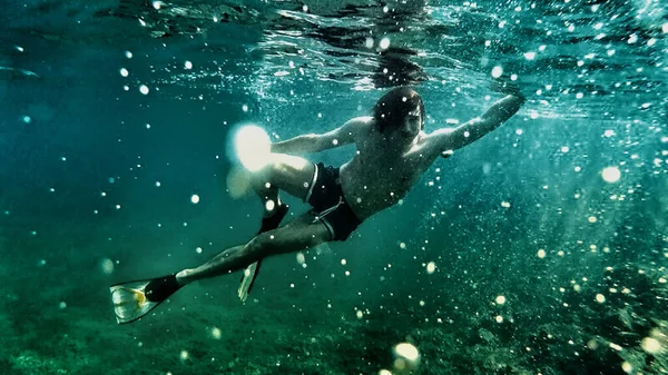 Underwater diving. Relaxation, sport, sunlight, travel, healthy lifestyle.  Guy is diving under water. Summer vacation concept.