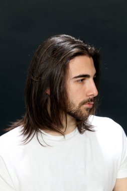 Uzun saçlı ve sakallı çekici erkek model izole bir arka planda stüdyoda poz veriyor. Tarz, trendler, moda konsepti.