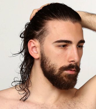 Uzun saçlı ve sakallı çekici erkek model izole bir arka planda stüdyoda poz veriyor. Tarz, trendler, moda konsepti.