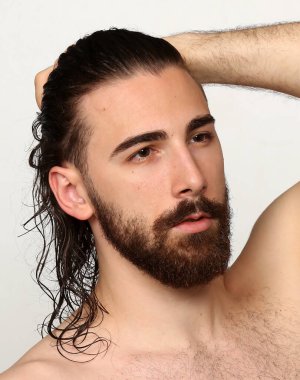 Uzun saçlı ve sakallı çekici erkek model izole bir arka planda stüdyoda poz veriyor. Tarz, trendler, moda konsepti.