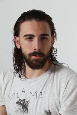 Uzun saçlı ve sakallı çekici erkek model izole bir arka planda stüdyoda poz veriyor. Tarz, trendler, moda konsepti.