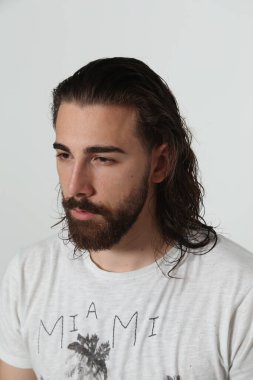Uzun saçlı ve sakallı çekici erkek model izole bir arka planda stüdyoda poz veriyor. Tarz, trendler, moda konsepti.