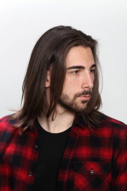 Uzun saçlı ve sakallı çekici erkek model izole bir arka planda stüdyoda poz veriyor. Tarz, trendler, moda konsepti.