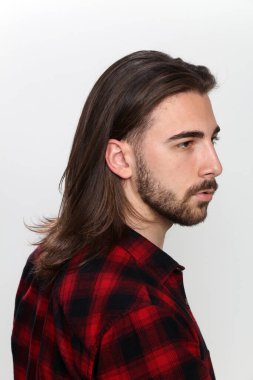 Uzun saçlı ve sakallı çekici erkek model izole bir arka planda stüdyoda poz veriyor. Tarz, trendler, moda konsepti.
