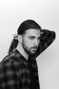 Uzun saçlı ve sakallı çekici erkek model izole bir arka planda stüdyoda poz veriyor. Tarz, trendler, moda konsepti.