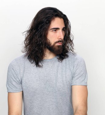 Uzun saçlı ve sakallı çekici erkek model izole bir arka planda stüdyoda poz veriyor. Tarz, trendler, moda konsepti.