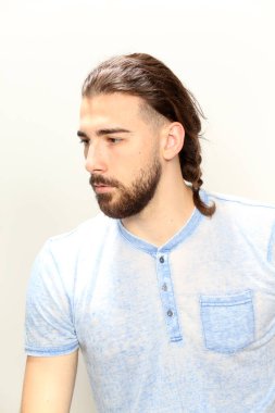 Uzun saçlı ve sakallı çekici erkek model izole bir arka planda stüdyoda poz veriyor. Tarz, trendler, moda konsepti.