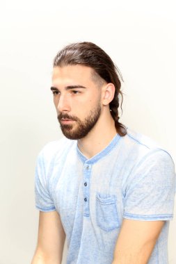 Uzun saçlı ve sakallı çekici erkek model izole bir arka planda stüdyoda poz veriyor. Tarz, trendler, moda konsepti.