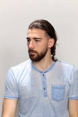 Uzun saçlı ve sakallı çekici erkek model izole bir arka planda stüdyoda poz veriyor. Tarz, trendler, moda konsepti.