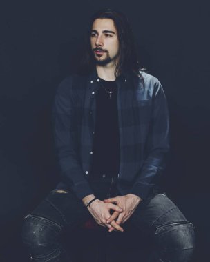 Uzun saçlı ve sakallı çekici erkek model izole bir arka planda stüdyoda poz veriyor. Tarz, trendler, moda konsepti.