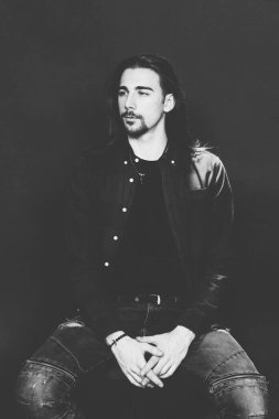 Uzun saçlı ve sakallı çekici erkek model izole bir arka planda stüdyoda poz veriyor. Tarz, trendler, moda konsepti.