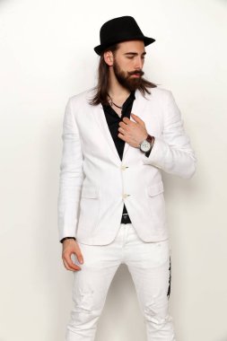 Genç, modaya uygun, uzun saçlı ve sakallı bir erkek model izole edilmiş arka planda stüdyoda poz veriyor. Moda, iş, modellik konsepti.