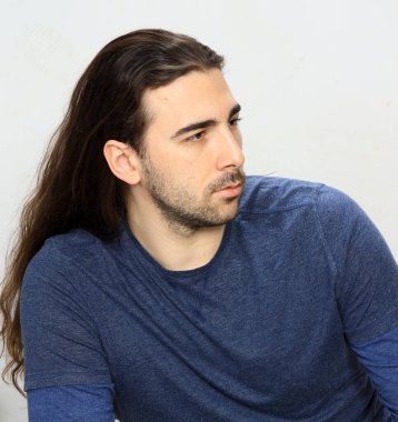 Uzun saçlı ve sakallı çekici erkek model stüdyoda poz veriyor. Tarz, trendler, moda konsepti.