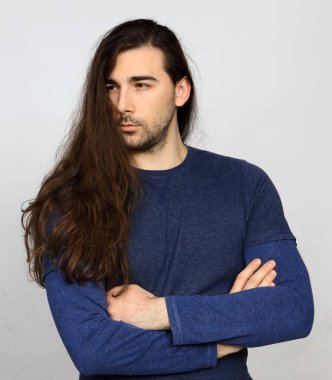 Uzun saçlı ve sakallı çekici erkek model stüdyoda poz veriyor. Tarz, trendler, moda konsepti.