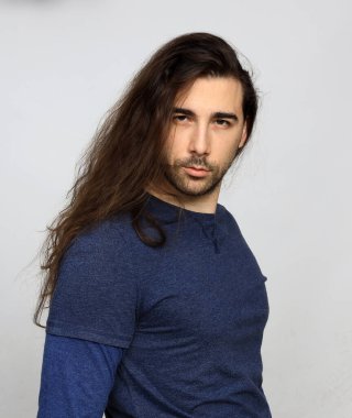 Uzun saçlı ve sakallı çekici erkek model stüdyoda poz veriyor. Tarz, trendler, moda konsepti.