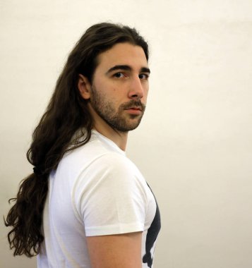 Uzun saçlı ve sakallı çekici erkek model stüdyoda poz veriyor. Tarz, trendler, moda konsepti.