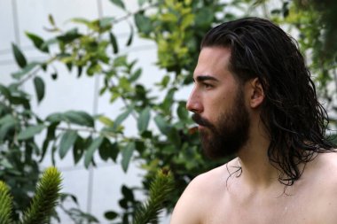 Genç, çekici erkek model, uzun saçlı ve sakallı, doğada poz veren. Tarz, trendler, moda konsepti.