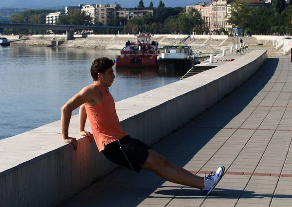 Young male athlete exercising by the Danube river at quay in Novi Sad, Serbia. Healthy lifestyle, outdoor running, sports concept.