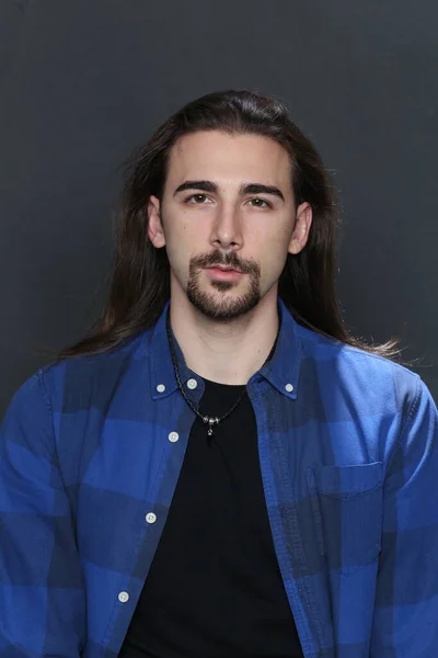 Attractive male model with long hair and beard posing in studio on isolated background. Style, trends, fashion concept.