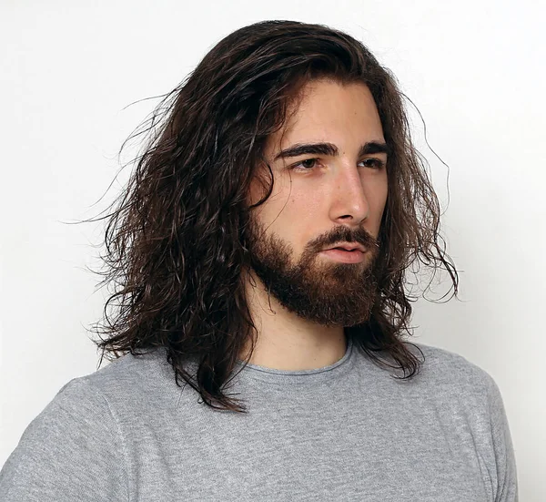 Uzun saçlı ve sakallı çekici erkek model izole bir arka planda stüdyoda poz veriyor. Tarz, trendler, moda konsepti.