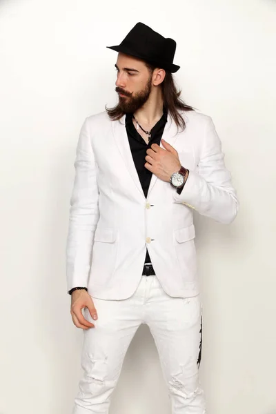 Young, fashionable male model with long hair and beard posing in studio on isolated background. Fashion, business, modeling concept.