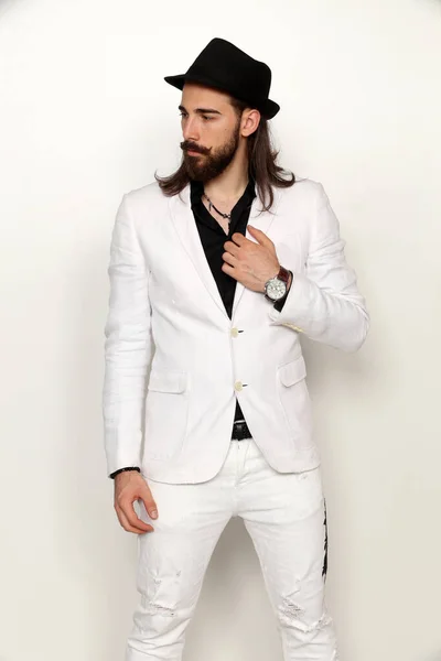 Young, fashionable male model with long hair and beard posing in studio on isolated background. Fashion, business, modeling concept.