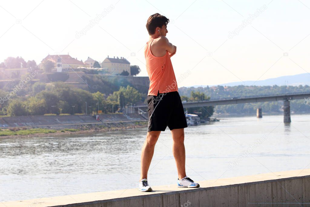 Young male athlete exercising by the Danube river at quay in Novi Sad, Serbia. Healthy lifestyle, outdoor running, sports concept.