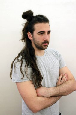 Çekici, sakallı, uzun saçlı, evde poz veren genç erkek model. Tarz, trendler, moda konsepti.