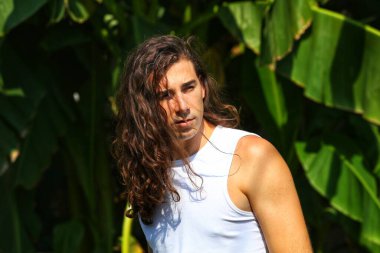 Çok uzun saçlı çekici bir adam vahşi doğada poz veriyor. Modelleme ve Moda Konsepti.