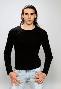 Uzun saçlı, çekici bir erkek model. Stüdyoda poz veriyor. Tarz, trendler, moda konsepti.