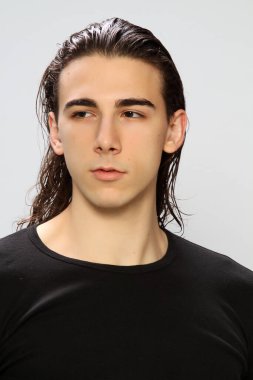 Uzun saçlı, çekici bir erkek model. Stüdyoda poz veriyor. Tarz, trendler, moda konsepti.