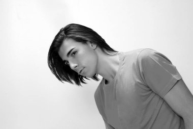 Uzun saçlı, çekici bir erkek model. Stüdyoda poz veriyor. Tarz, trendler, moda konsepti.