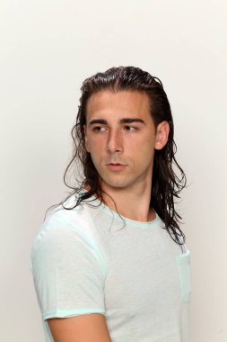 Uzun saçlı, çekici bir erkek model. Stüdyoda poz veriyor. Tarz, trendler, moda konsepti.