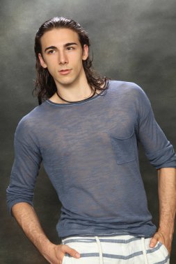 Uzun saçlı, çekici bir erkek model. Stüdyoda poz veriyor. Tarz, trendler, moda konsepti.