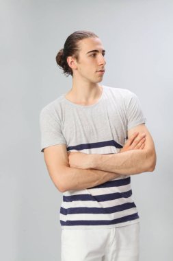 Uzun saçlı, çekici bir erkek model. Stüdyoda poz veriyor. Tarz, trendler, moda konsepti.