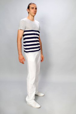 Uzun saçlı, çekici bir erkek model. Stüdyoda poz veriyor. Tarz, trendler, moda konsepti.