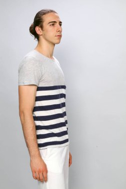 Uzun saçlı, çekici bir erkek model. Stüdyoda poz veriyor. Tarz, trendler, moda konsepti.