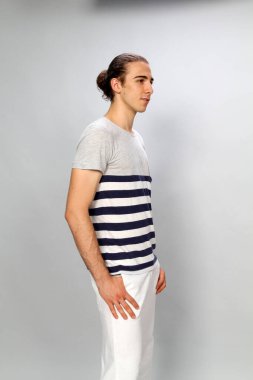 Uzun saçlı, çekici bir erkek model. Stüdyoda poz veriyor. Tarz, trendler, moda konsepti.