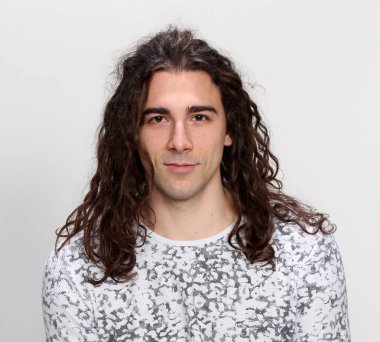 Uzun saçlı, çekici bir erkek model. Stüdyoda poz veriyor. Tarz, trendler, moda konsepti.