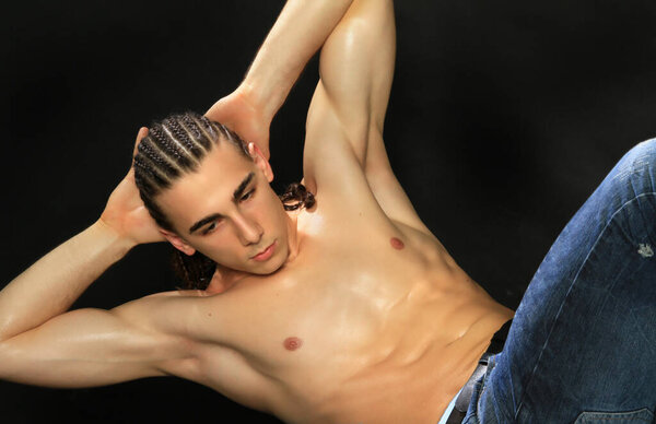 Привлекательная мужская модель с длинными волосами позирует в студии на изолированном фоне. Стиль, тенденции, концепция моды.