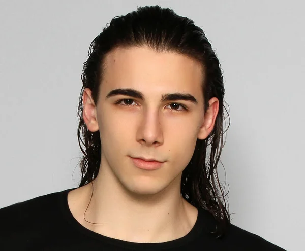 Attractive male model with long hair posing in studio on isolated background. Style, trends, fashion concept.