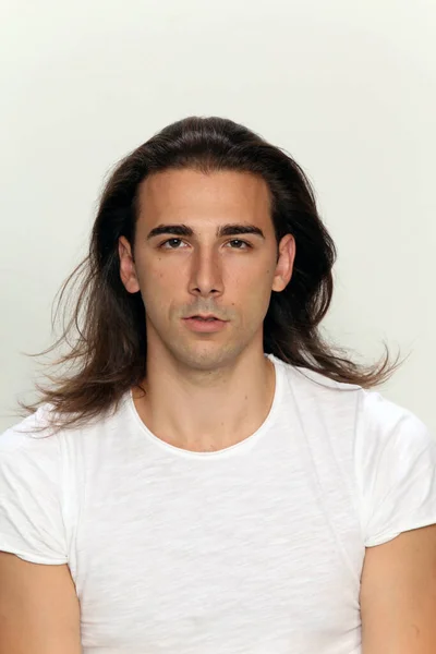 Attractive male model with long hair posing in studio on isolated background. Style, trends, fashion concept.