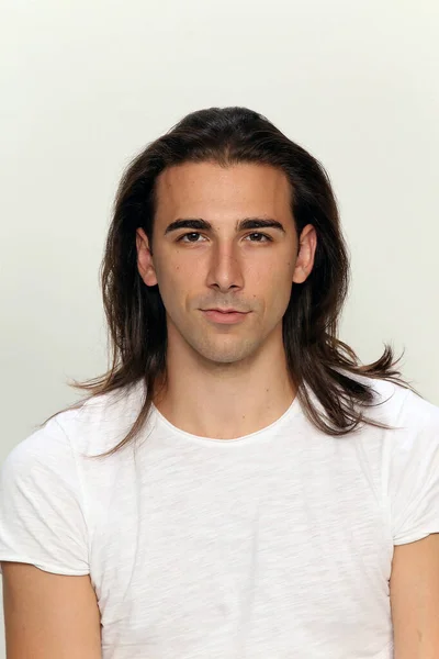 Attractive male model with long hair posing in studio on isolated background. Style, trends, fashion concept.