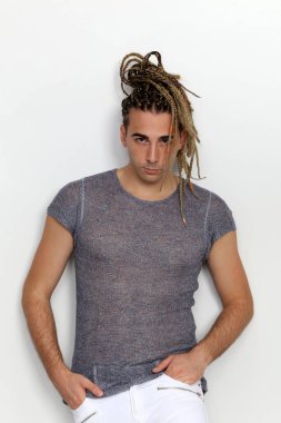 Çekici sarışın erkek model. Örgü ve rastalı saç örgülerinin kombinasyonu. Stüdyoda izole edilmiş arka planda poz veriyor. Tarz, trendler, moda konsepti.