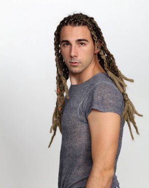 Çekici sarışın erkek model. Örgü ve rastalı saç örgülerinin kombinasyonu. Stüdyoda izole edilmiş arka planda poz veriyor. Tarz, trendler, moda konsepti.