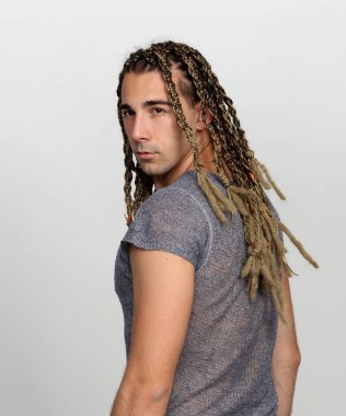 Çekici sarışın erkek model. Örgü ve rastalı saç örgülerinin kombinasyonu. Stüdyoda izole edilmiş arka planda poz veriyor. Tarz, trendler, moda konsepti.