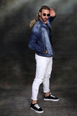 Çekici sarışın erkek model. Örgü ve rastalı saç örgülerinin kombinasyonu. Stüdyoda izole edilmiş arka planda poz veriyor. Tarz, trendler, moda konsepti.