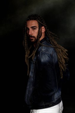 Çekici sarışın erkek model. Örgü ve rastalı saç örgülerinin kombinasyonu. Stüdyoda izole edilmiş arka planda poz veriyor. Tarz, trendler, moda konsepti.