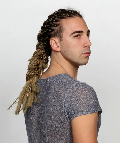 Attractive blonde male model with combination of braids and dreadlocks posing in studio on isolated background. Style, trends, fashion concept.